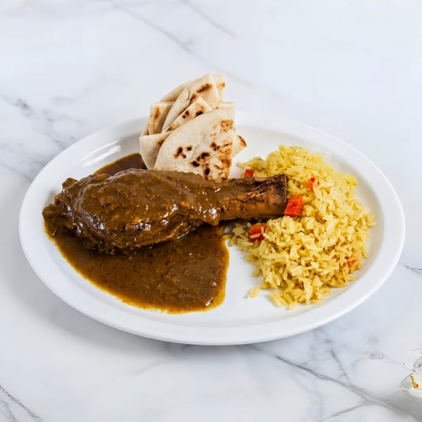 Chicken leg in brown sauce with yellow rice and flatbread on a white plate.