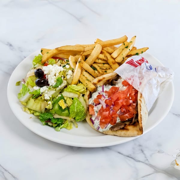 A gyro with fries and a Greek salad with feta cheese and olives on a white plate.